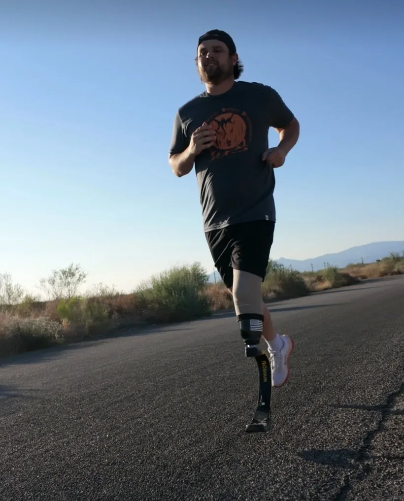 Dallas Reign, founder of PhantomTech Labs, running on a desert road wearing a running-blade prosthetic leg
